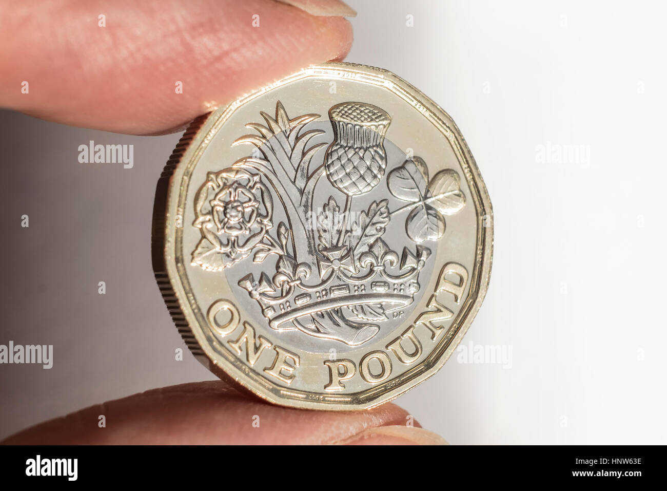 Nuovo design pound moneta trattenuta tra le dita Foto Stock