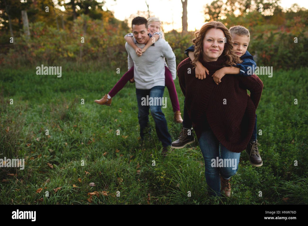 I genitori dare ai bambini piggy back nel campo Foto Stock