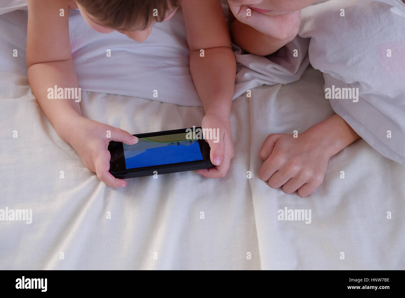 I bambini giocando su telefono cellulare a letto Foto Stock