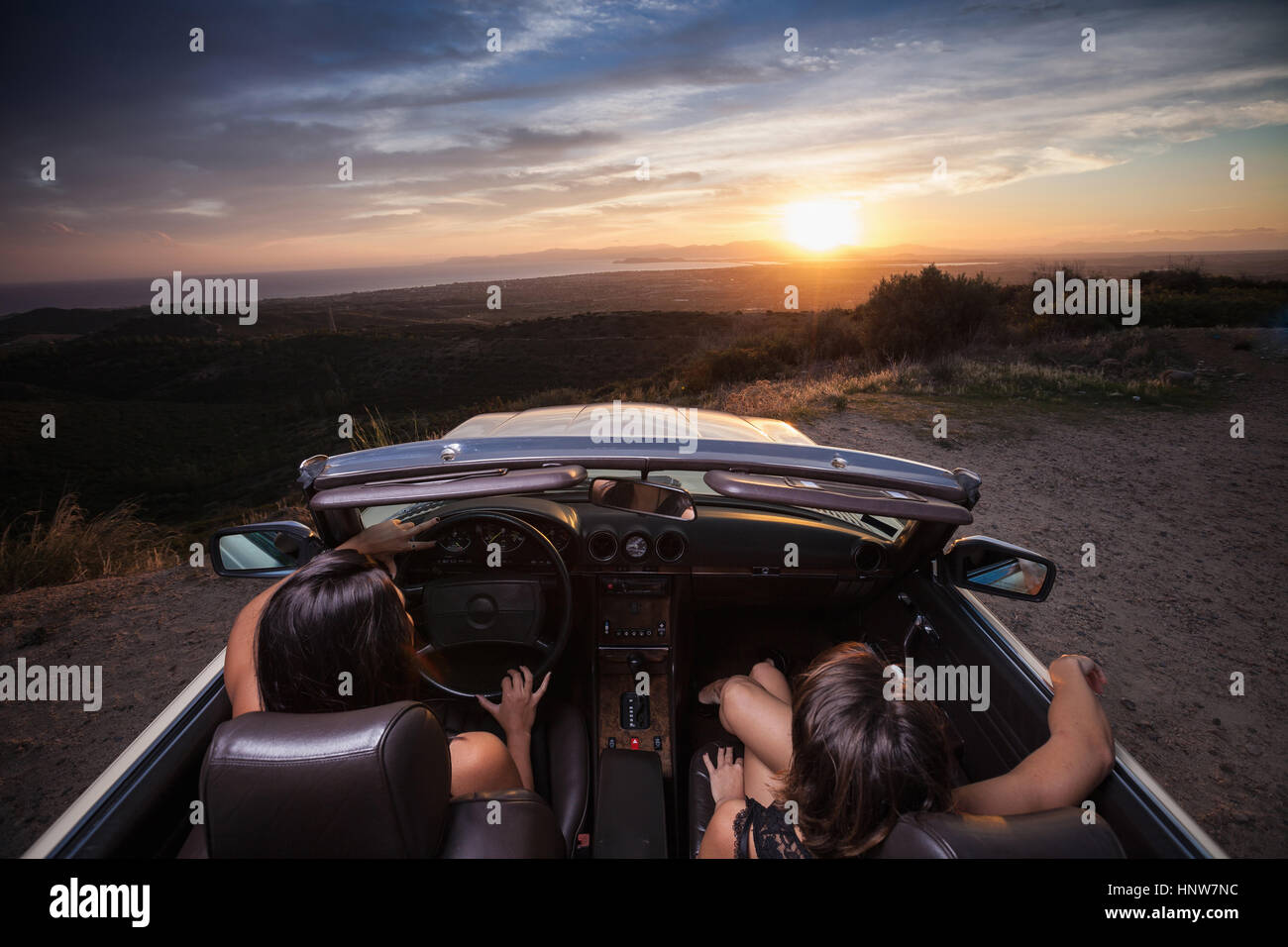 Due giovani donne in autovettura convertibile, guidando lungo la strada panoramica, vista posteriore Foto Stock