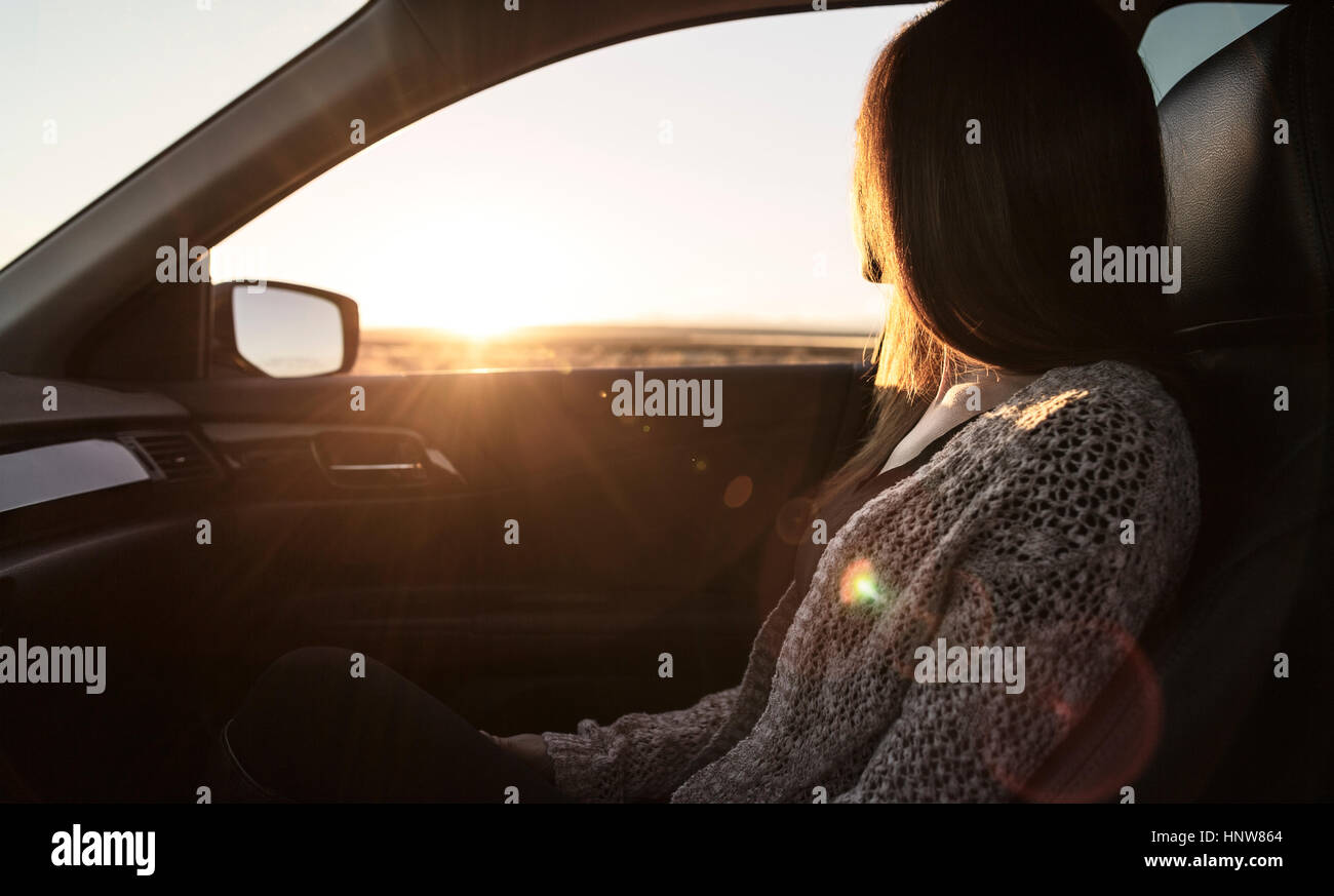 Giovane donna seduta nel sedile del passeggero di auto, guardando fuori della finestra Foto Stock