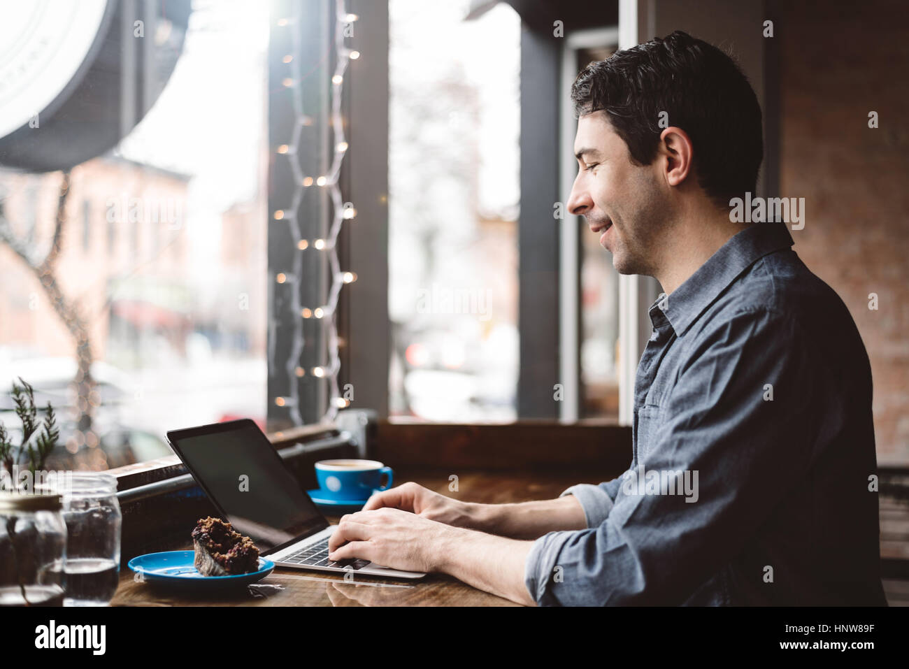 Uomo al lavoro su computer portatile presso il cafe Foto Stock