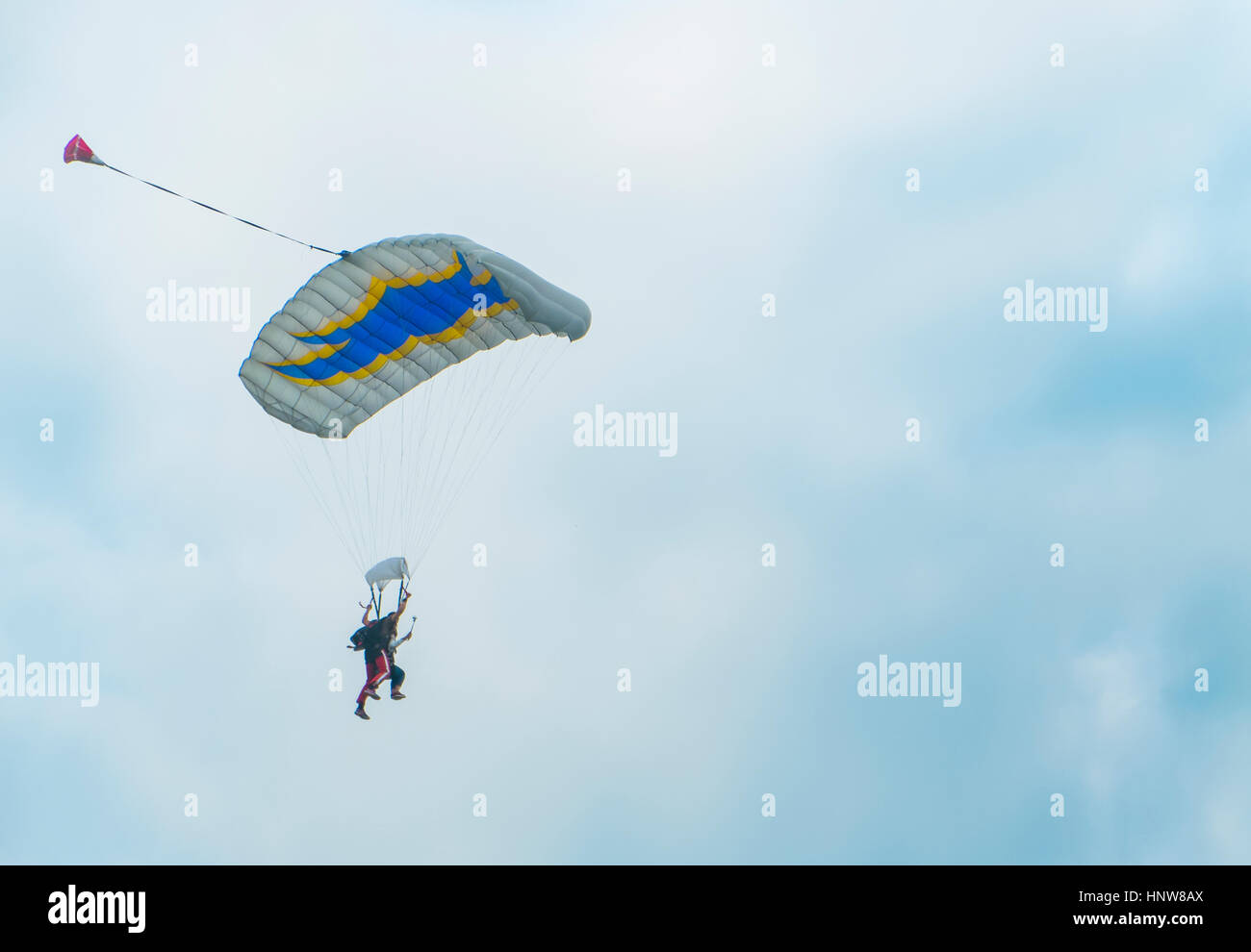 Vista del paracadutismo in tandem verso il basso contro il cielo nuvoloso Foto Stock