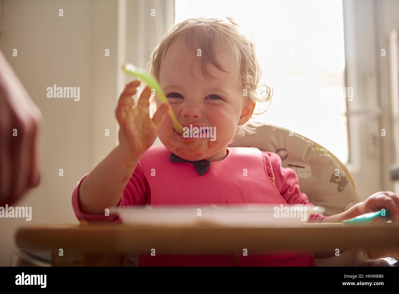 Bambino seduto nel seggiolone, mangiare il pasto Foto Stock