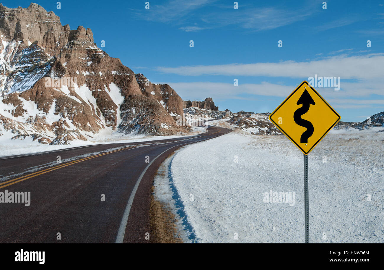 Curve strette un cartello di segnalazione: Un segno avverte di una torsione strada su una giornata invernale nel Parco nazionale Badlands. Foto Stock