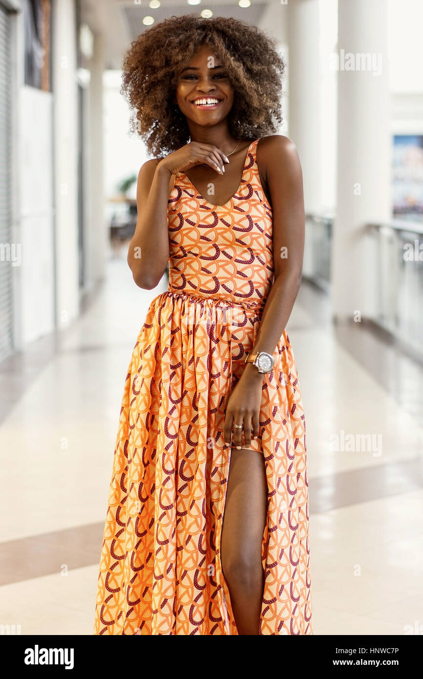 Capelli ricci afro-americane ragazza in un abito lungo in piedi in un  centro commerciale per lo shopping Foto stock - Alamy