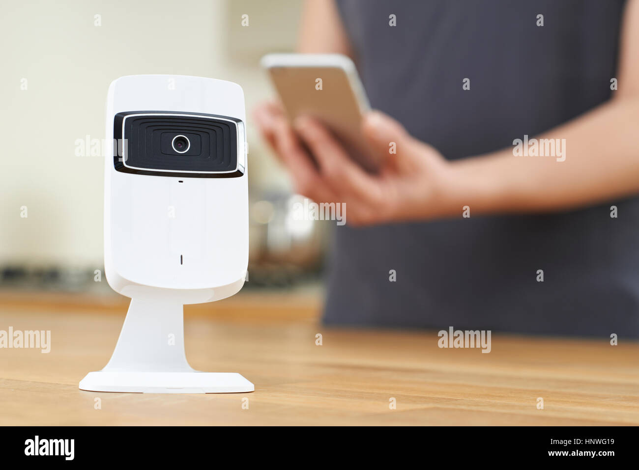 La donna il controllo Smart videocamera di sicurezza utilizzando l'App sul telefono cellulare Foto Stock