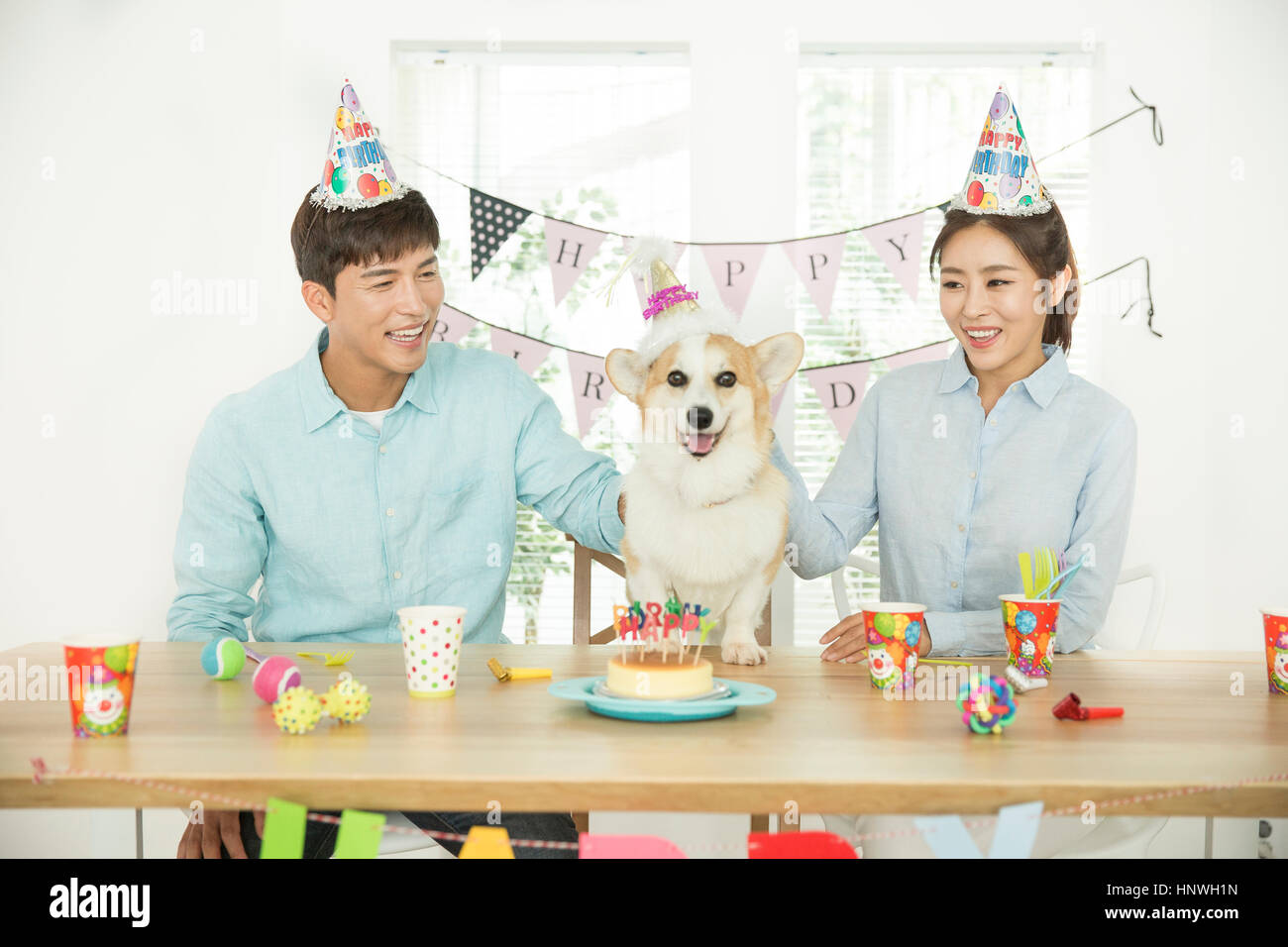 Coppia sorridente con il cane alla festa di compleanno Foto Stock