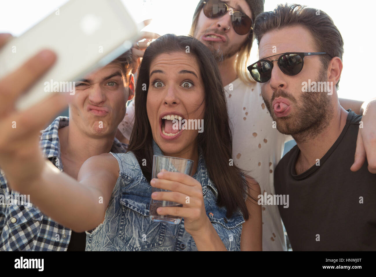 Giovani amici adulti tirando facce per selfie presso la terrazza sul tetto delle parti Foto Stock
