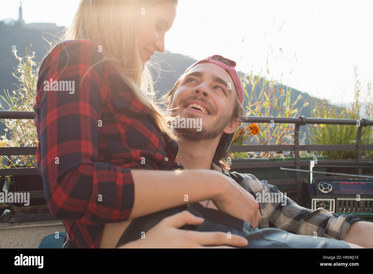 Giovane donna seduta sul ragazzo giro sulla terrazza sul tetto Foto Stock