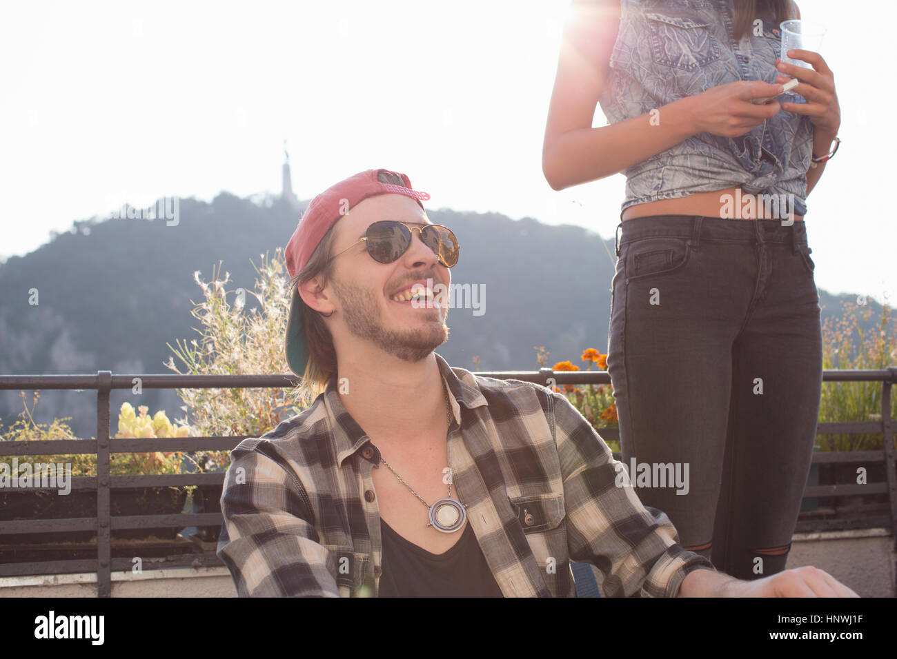 Felice giovane alla soleggiata terrazza sul tetto delle parti Foto Stock