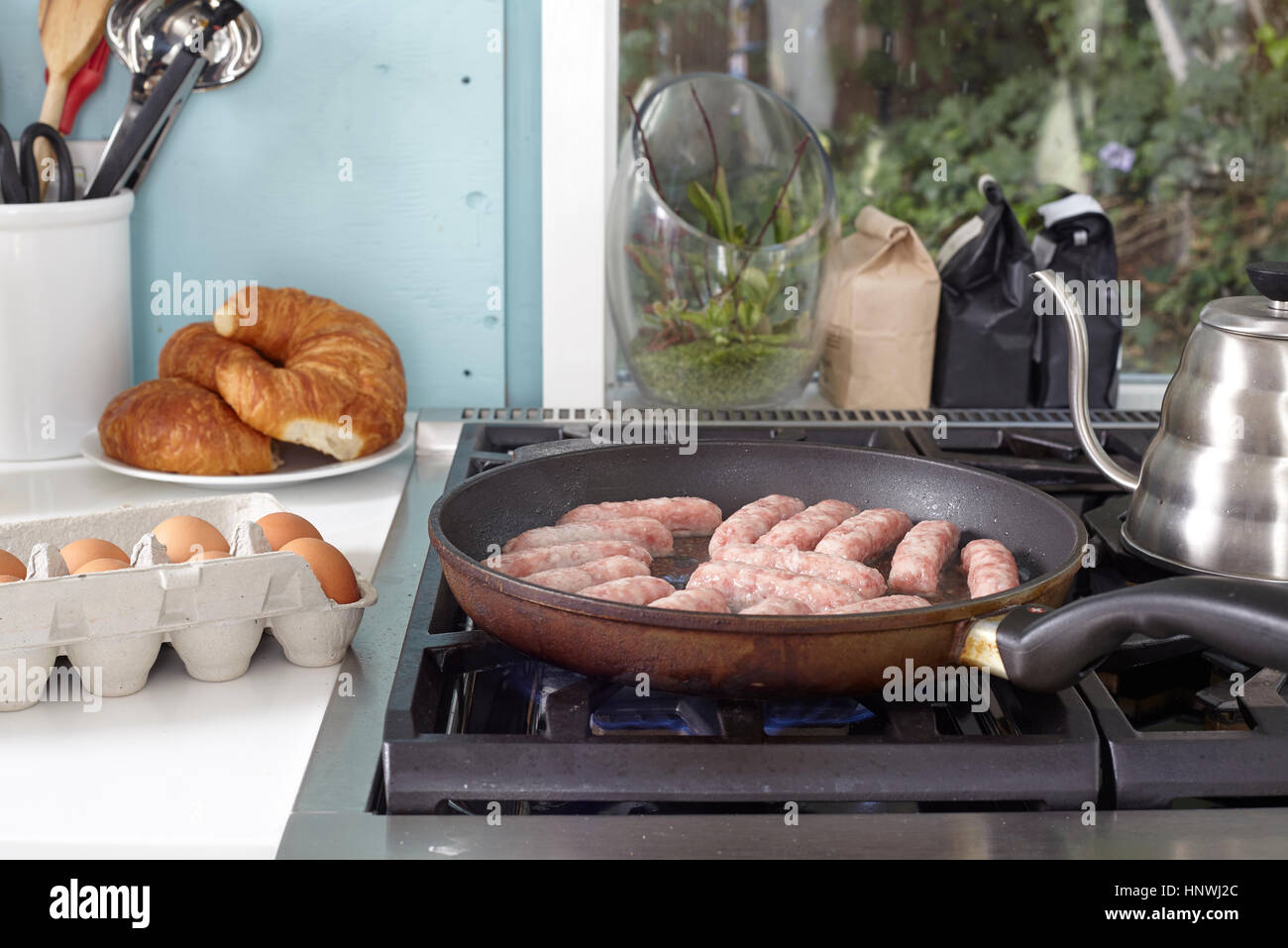 La colazione salsicce frittura in padella sul piano di cottura Foto Stock