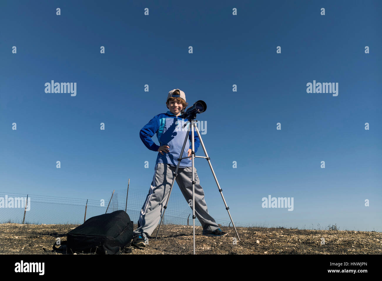 Ragazzo dietro il telescopio su treppiede Foto Stock