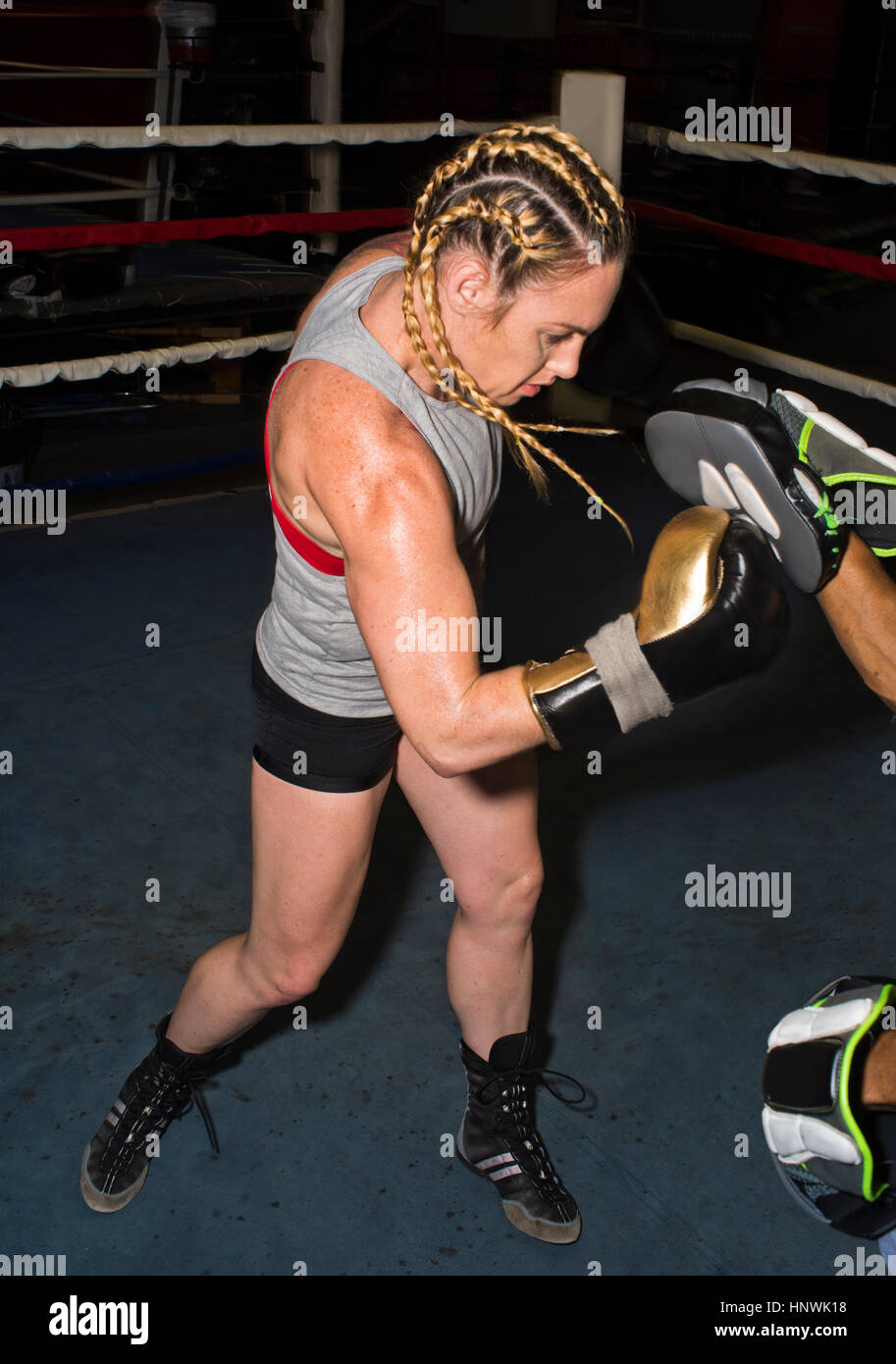 Boxer femmina la punzonatura del formatore guanto boxe nel pugilato ring Foto Stock