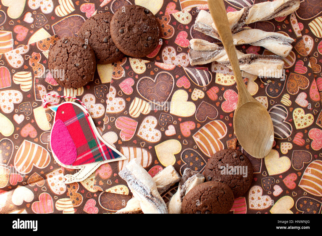 Rosso uccello giocattolo e cookie sul tovagliolo scuro con immagine di heartsclose fino. Vista superiore, piatto laici. Foto Stock