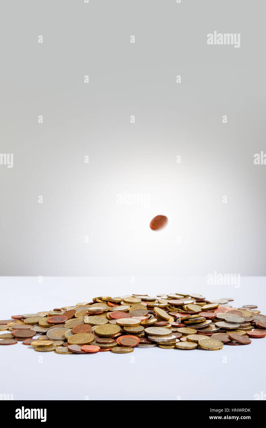 Illuminated Euro moneta che cade su di un sacco di monete Foto Stock