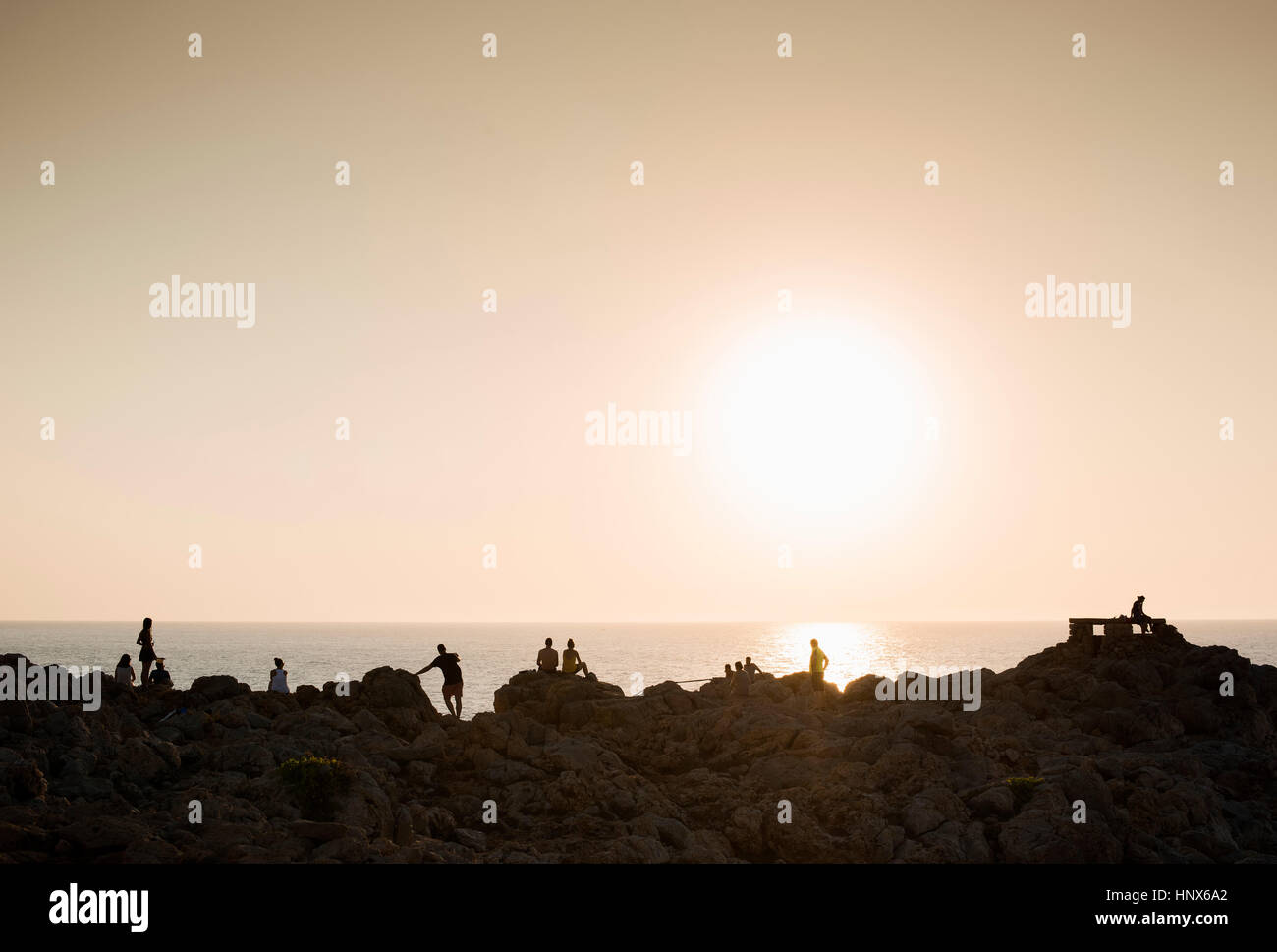 Silhouette di persone sulle rocce al tramonto, Ciutadella, Menorca, Spagna Foto Stock