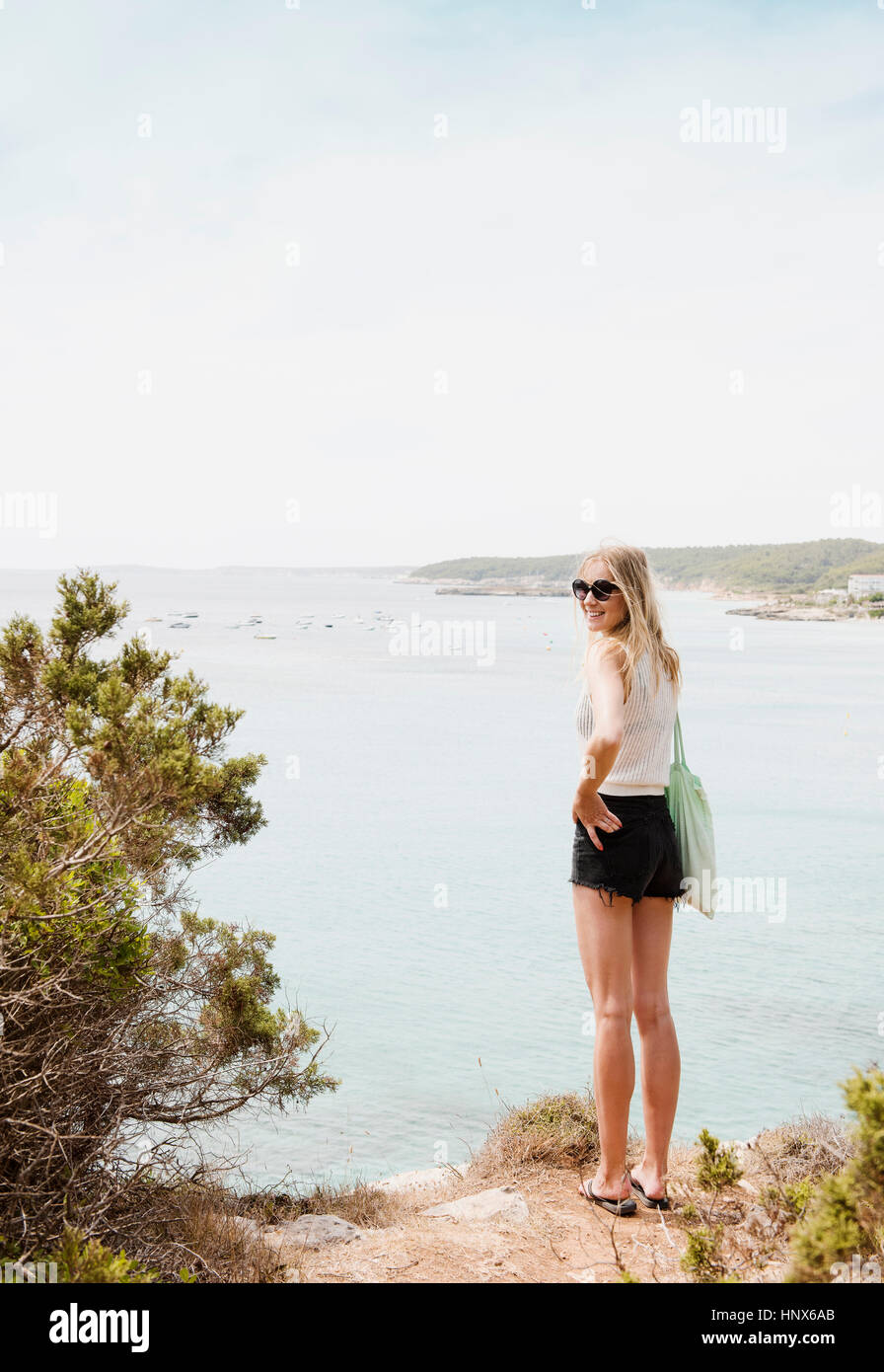 Donna di mare guardando sopra la spalla in telecamera sorridente, Menorca, Spagna Foto Stock