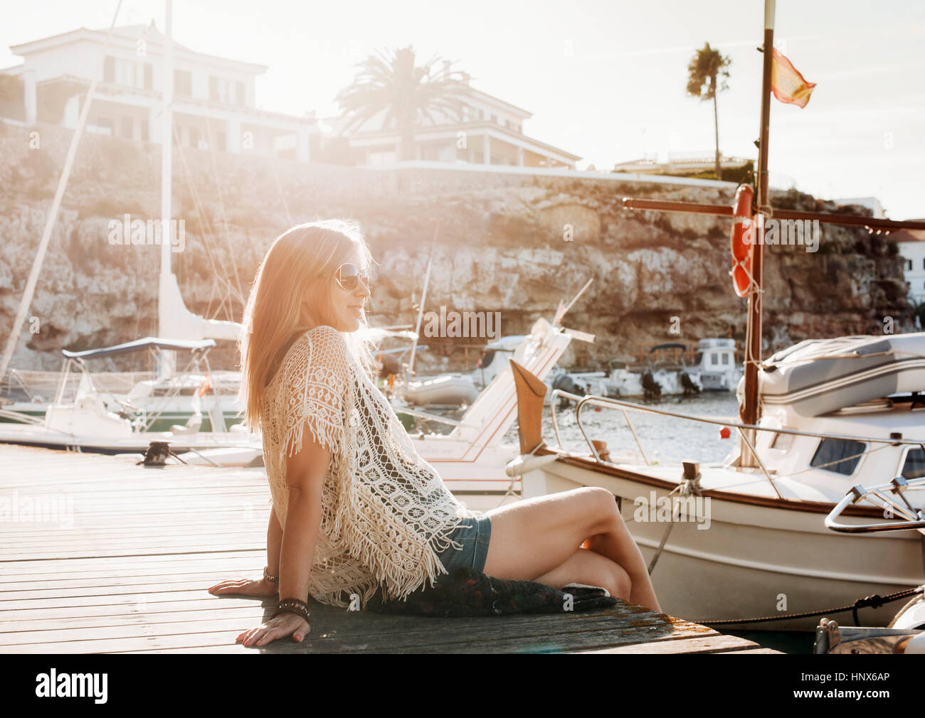 Donna seduta con le barche in marina, Es Castell, Menorca, Spagna Foto Stock