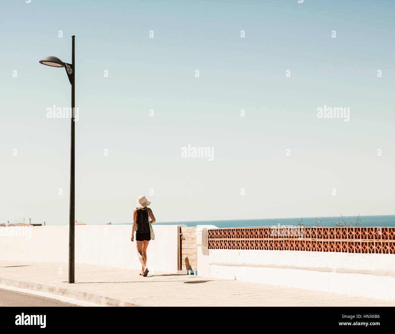 Vista posteriore della donna che cammina in strada, Menorca, Spagna Foto Stock
