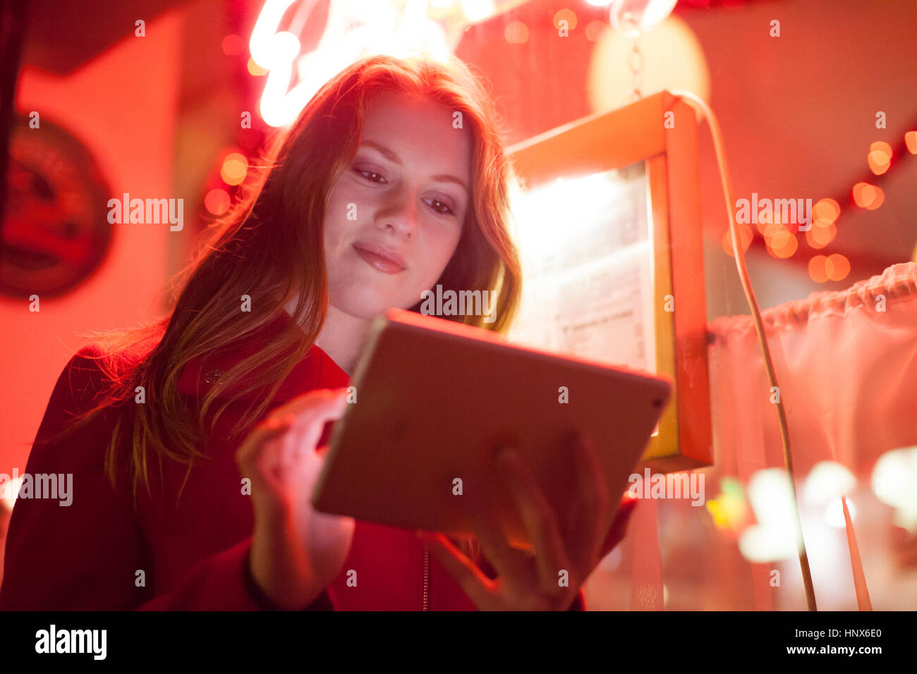 Giovane donna con tavoletta digitale nelle insegne al neon shop, London, Regno Unito Foto Stock