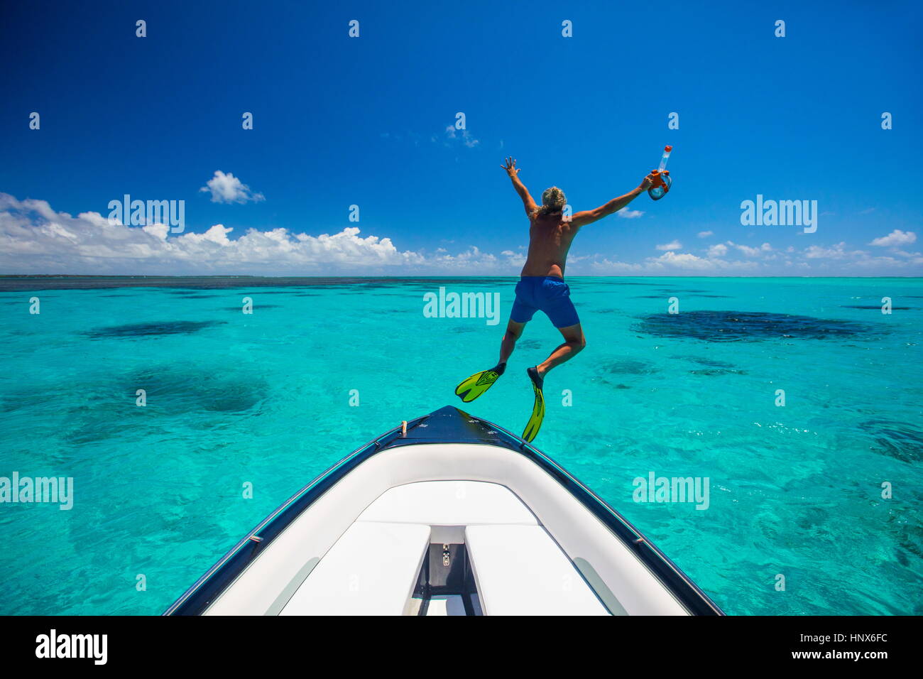 Uomo maturo, indossare pinne, salta fuori da barca, Ile aux Cerfs, Mauritius Foto Stock