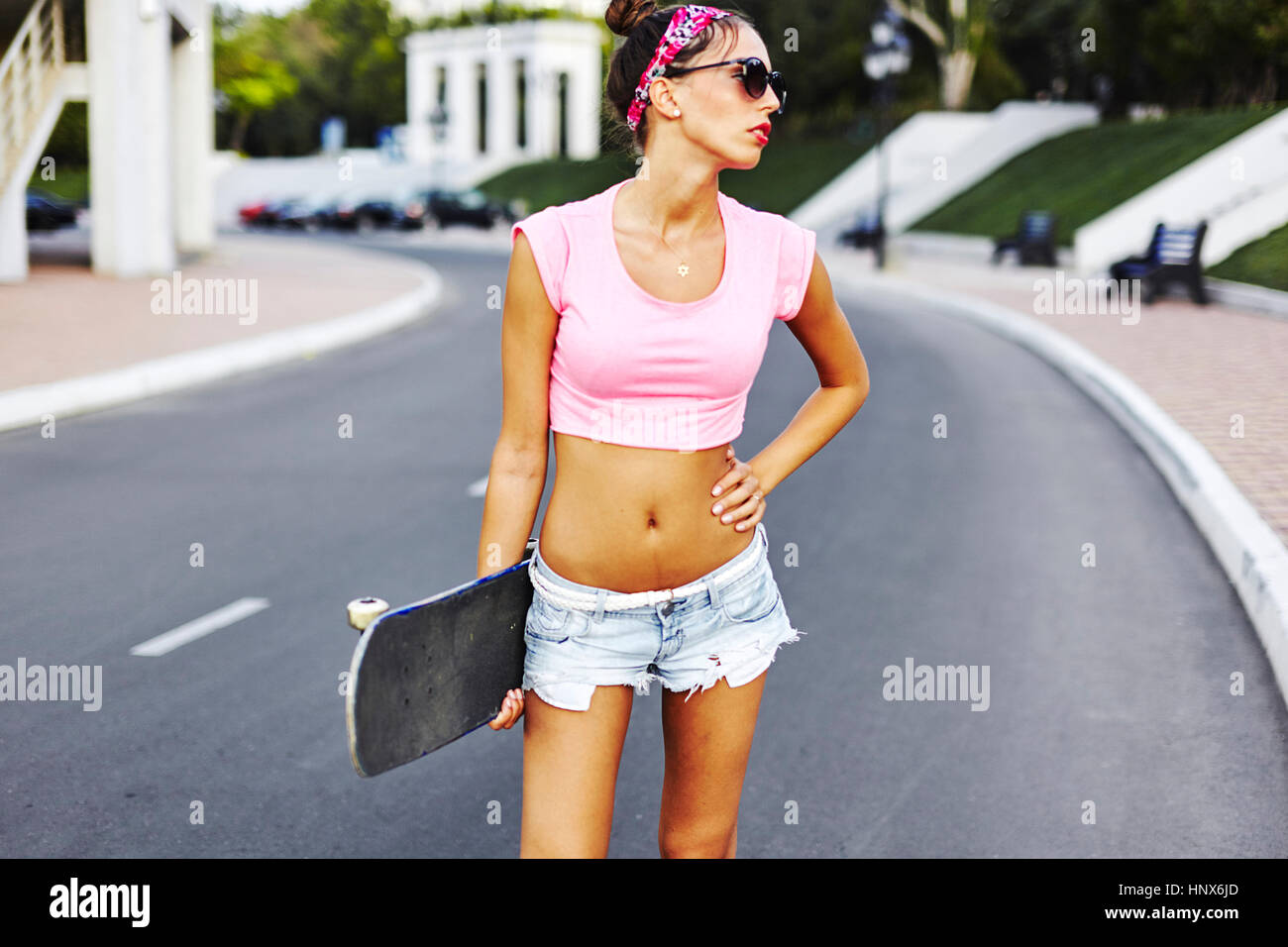 Ritratto di giovane donna in piedi in strada, azienda skateboard Foto Stock
