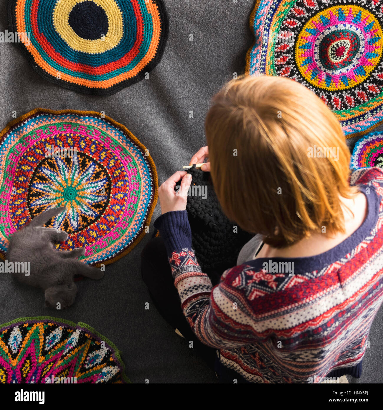 Vista aerea della donna seduta sul pavimento a crochet, circondato da cerchi a crochet Foto Stock