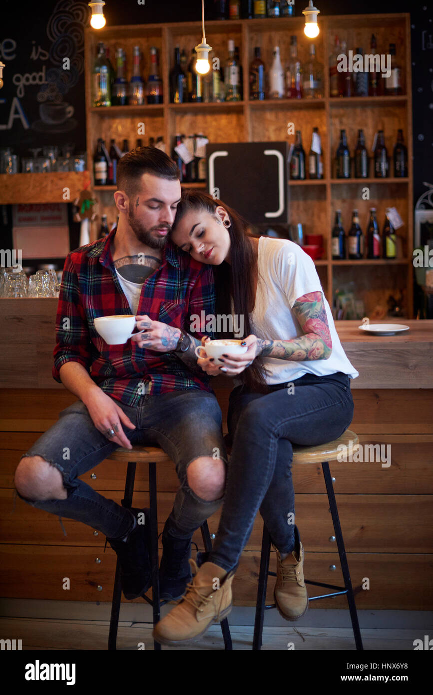 Giovane seduti fianco a fianco su sgabelli in cafe, la testa sulla spalla Foto Stock