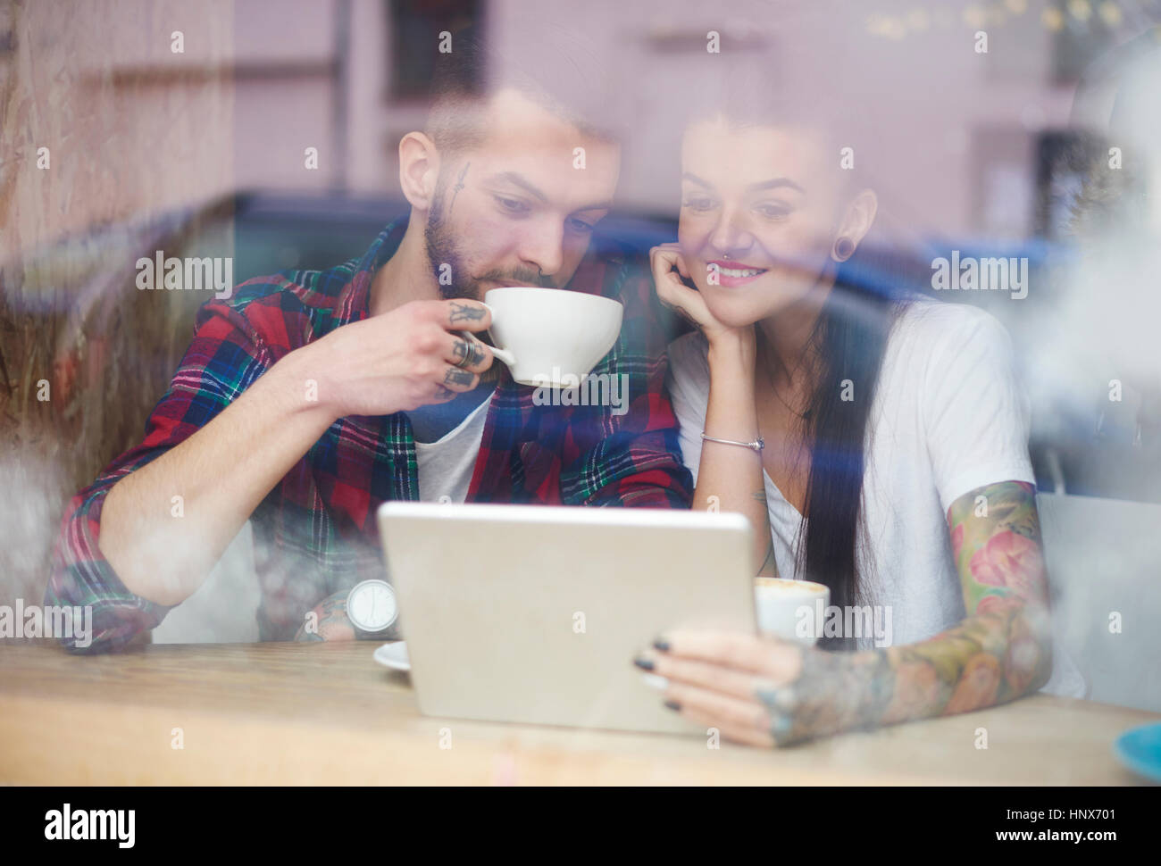 Vista attraverso la finestra del giovane nel coffee shop con tavoletta digitale Foto Stock