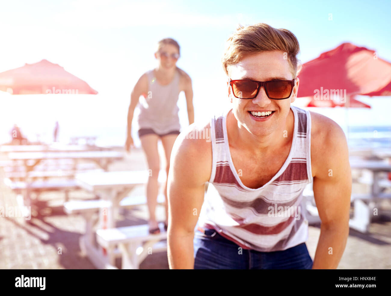 Ritratto di uomo che indossa gli occhiali da sole guardando sorridente della fotocamera Foto Stock