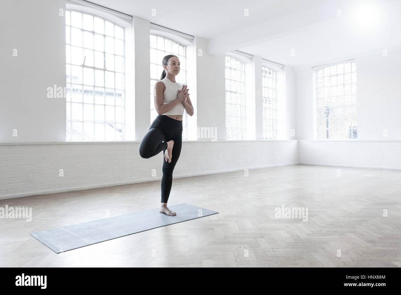 Donna in studio di danza in piedi su una gamba in posizione di yoga Foto Stock