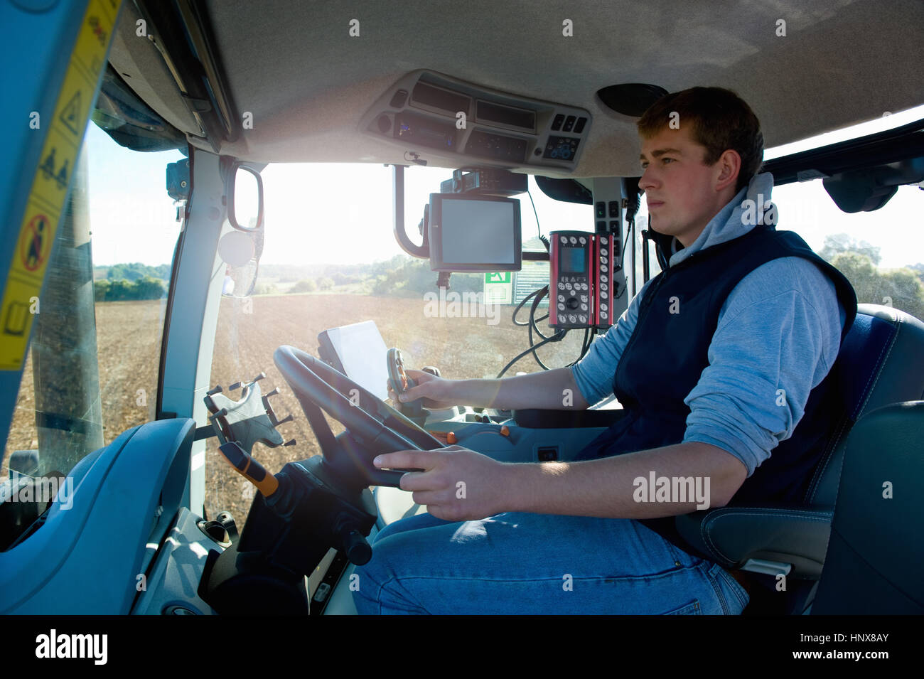 Giovane uomo guida del trattore utilizzando il sistema di posizionamento globale Foto Stock