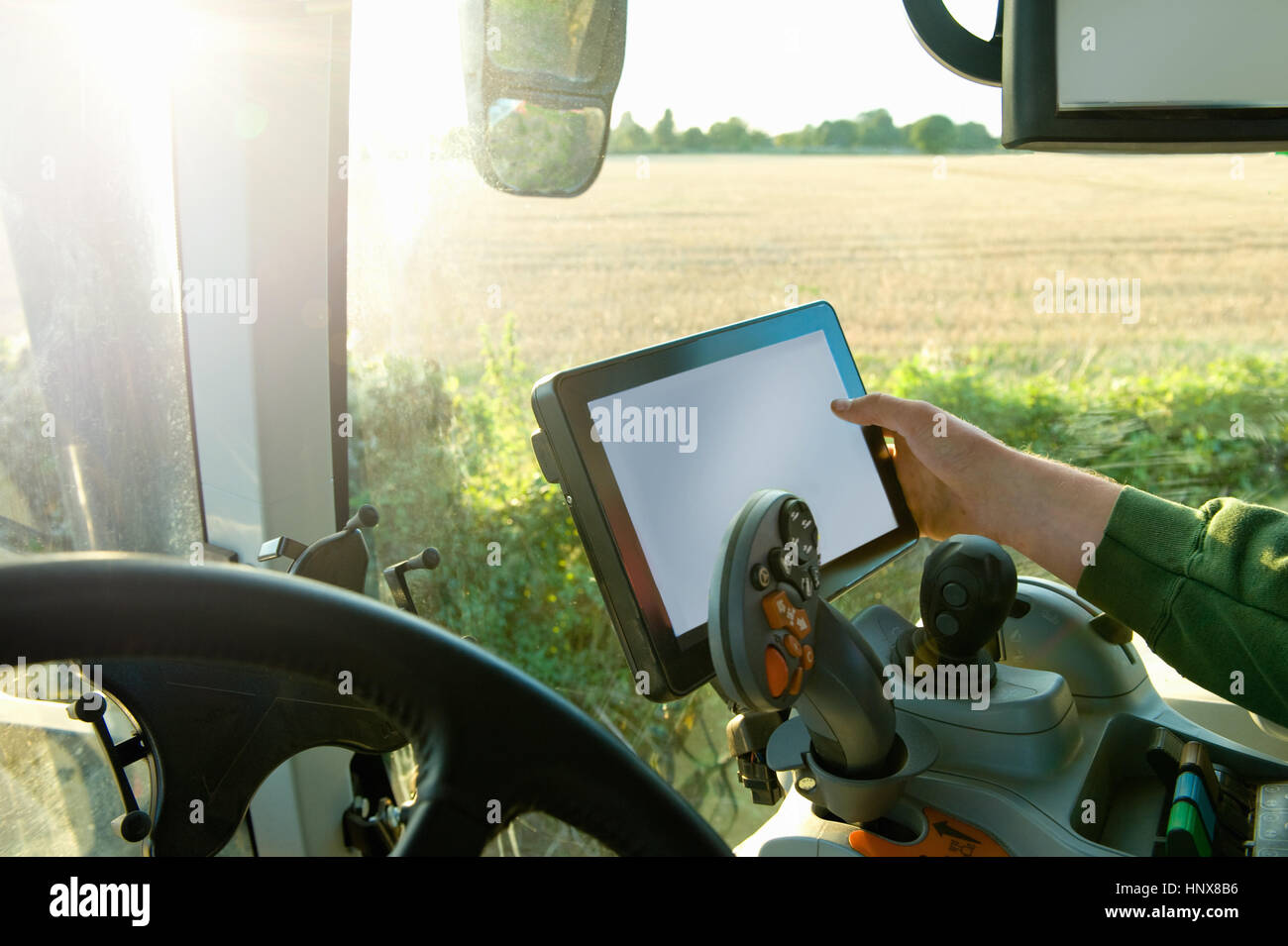 Agricoltore la mano la guida del trattore tramite il display tattile sul sistema di posizionamento globale Foto Stock