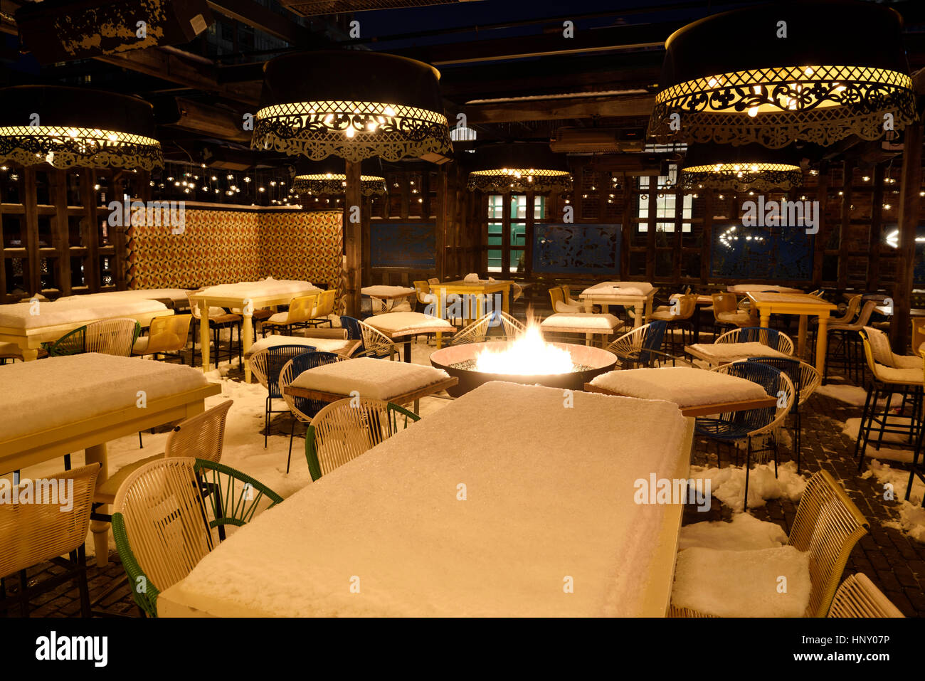 Neve coperti tavoli e sedie con una buca per il fuoco nella vuota patio esterno del distretto di distilleria ristorante Toronto Foto Stock