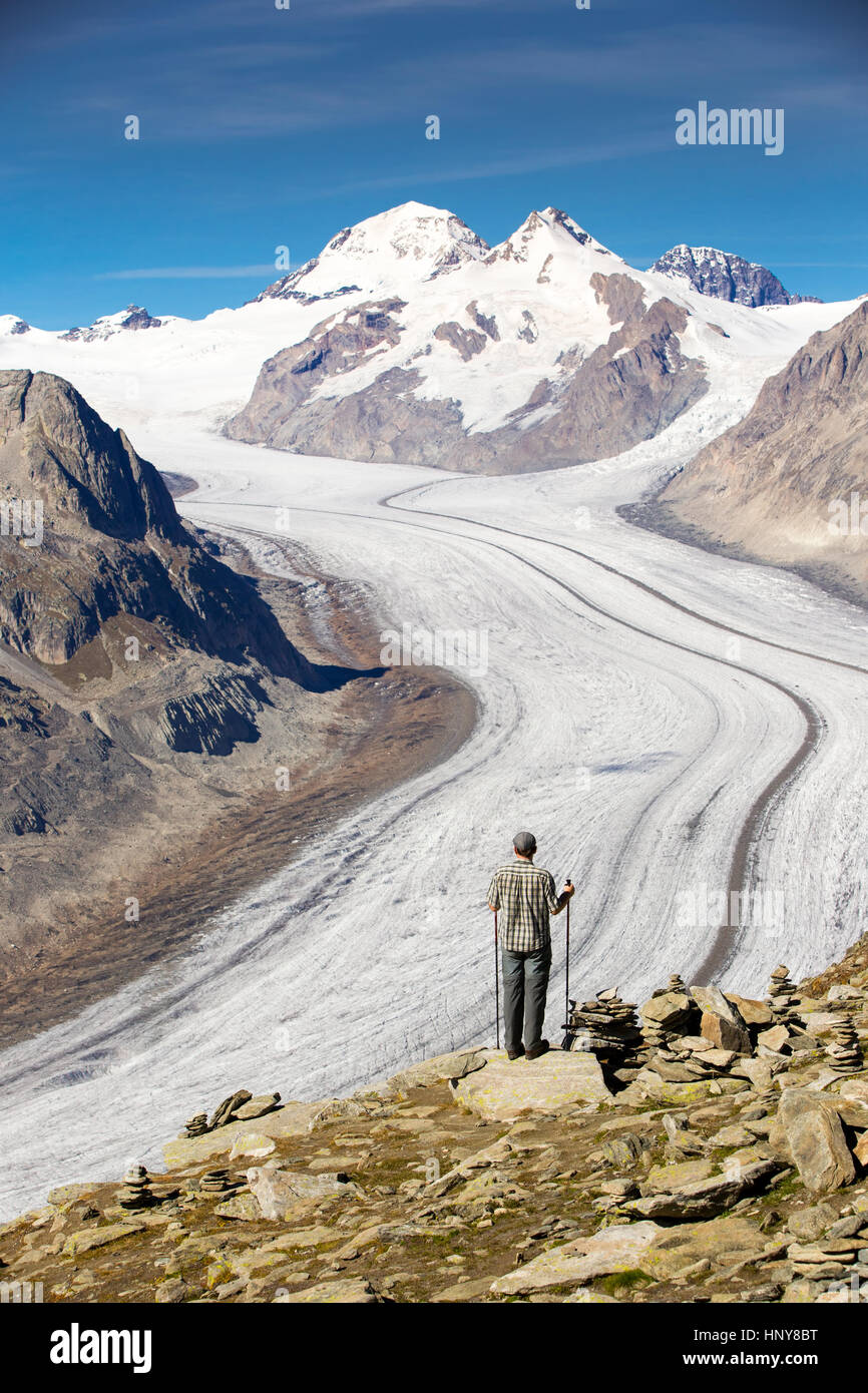 Giovane uomo guardando una vista maestosa al ghiacciaio di Aletsch, il più grande gracier nelle Alpi e UNESCO herritage da Bettmeralp, Vallese, Svizzera, Europa Foto Stock