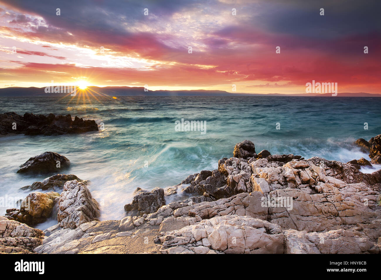 Sunrise oltre la spiaggia rocciosa sulla costa del Mare Adriatico, Istria, Croazia Foto Stock