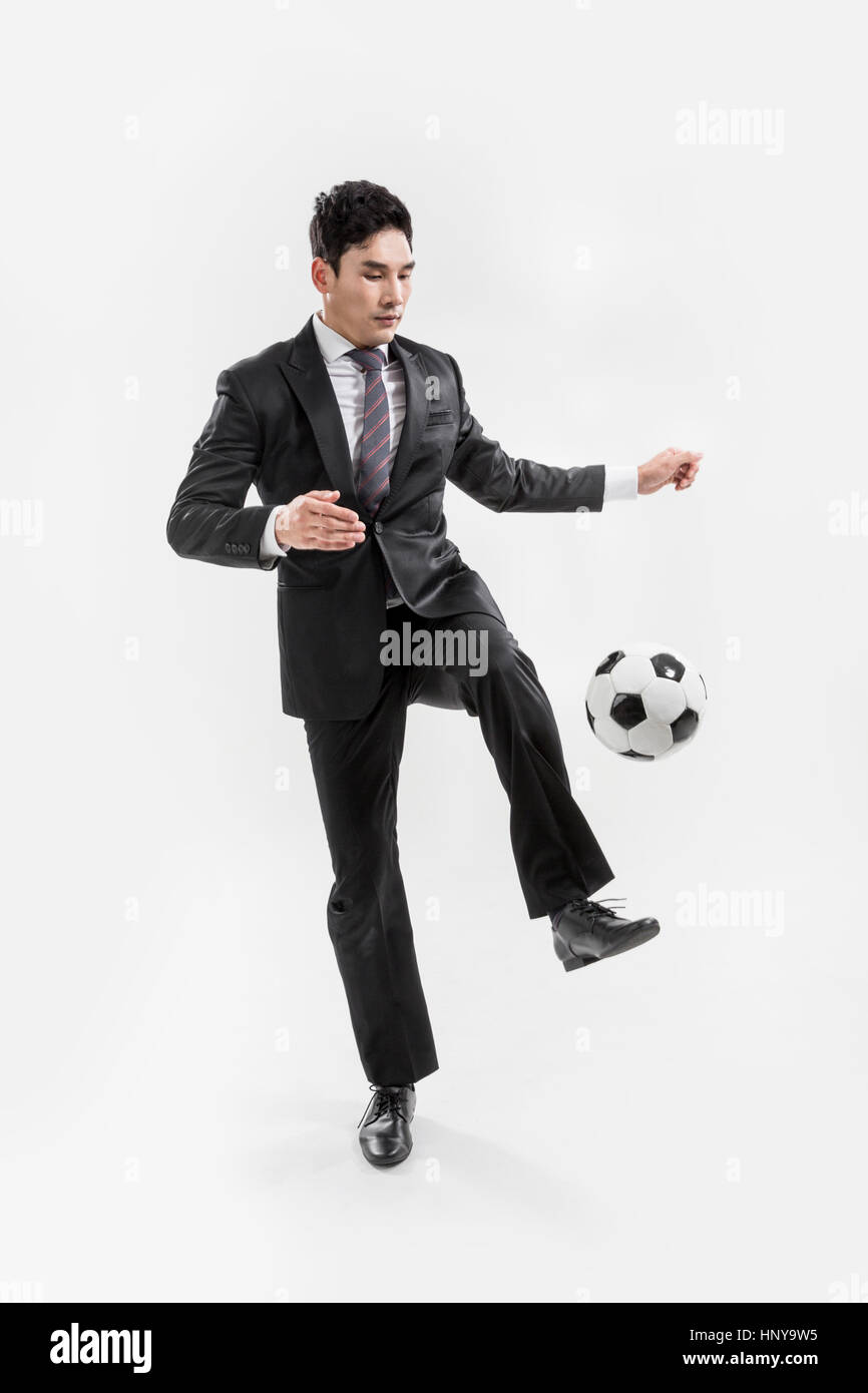 Imprenditore giocando con il pallone da calcio Foto Stock