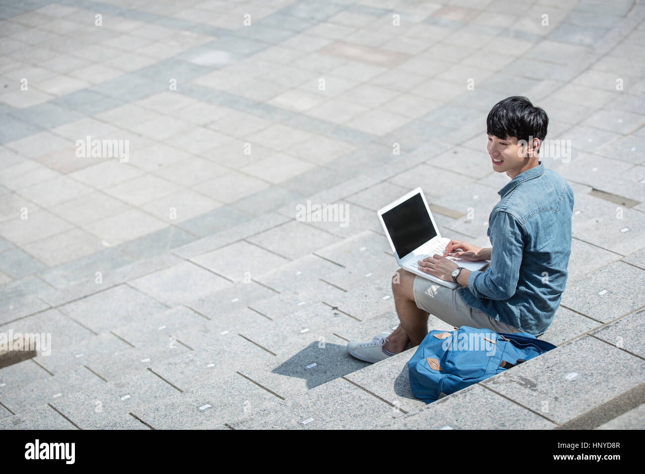 Maschio sorridente studente di college con seduta per laptop Foto Stock