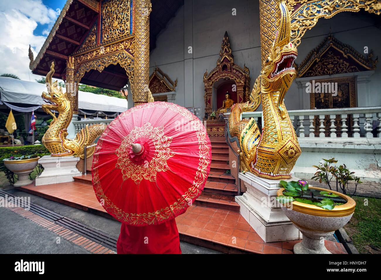 Donna con turistico rosso tailandese tradizionale ombrellone vicino a Golden tempio Wat Phra Singh con grandi statue di Drago in Chiang Mai Thailandia Foto Stock