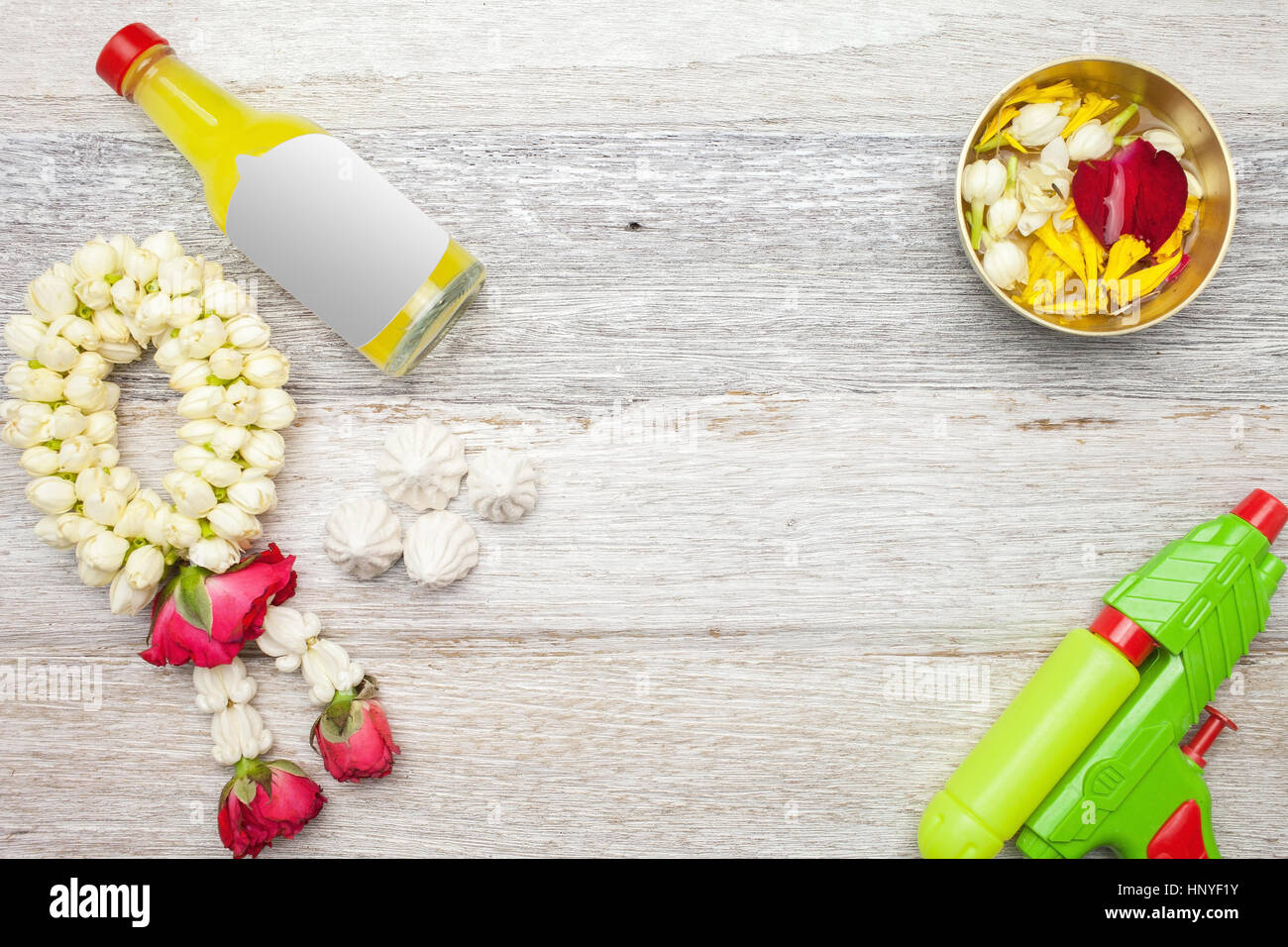 Songkran Festival : Profumo,ghirlanda floreale,,alimentazione e pistola sul bianco sullo sfondo di legno Foto Stock