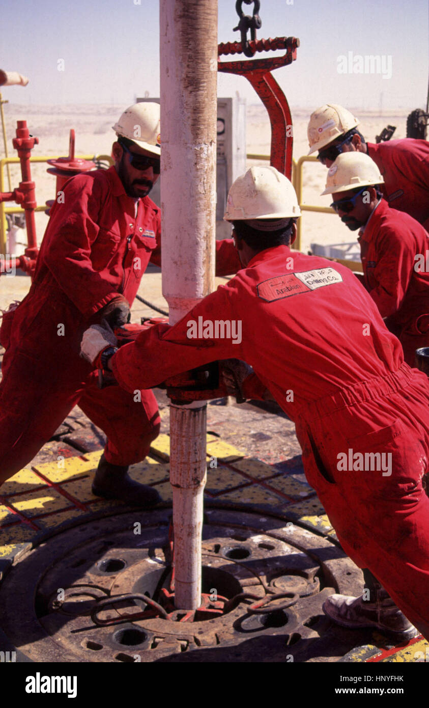 Roustabouts sul trapano il carico sul pavimento involucro come essi trapanare per olio in Arabia deserto vicino Abqaiq, da Le Mille e Una compagnia di trivellazione, assunti dalla Saudi Aramco, i mondi più grande produttore di petrolio. Foto Stock