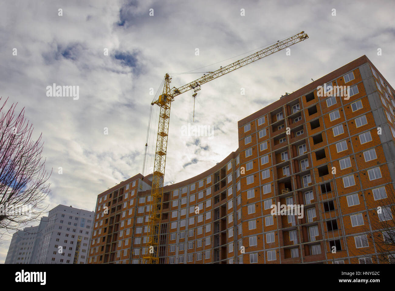 La gru e la costruzione dell'edificio sito contro il cielo blu. Foto Stock