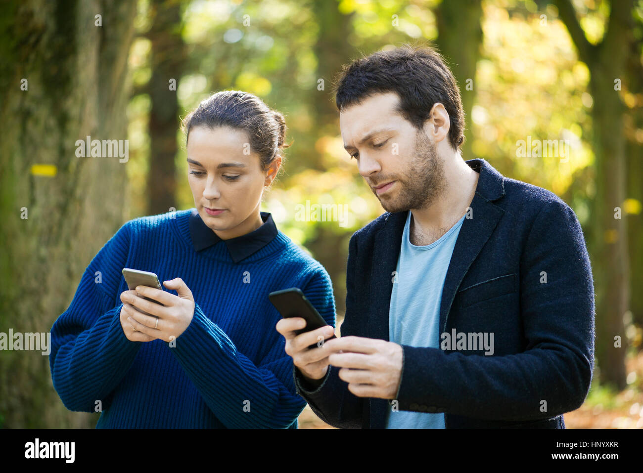 Accoppiare gli smartphone di controllo mentre si cammina nel bosco Foto Stock