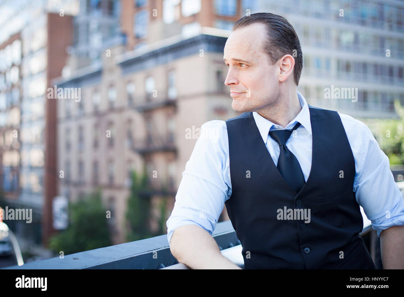 Imprenditore in piedi sul balcone, che guarda lontano nel pensiero Foto Stock