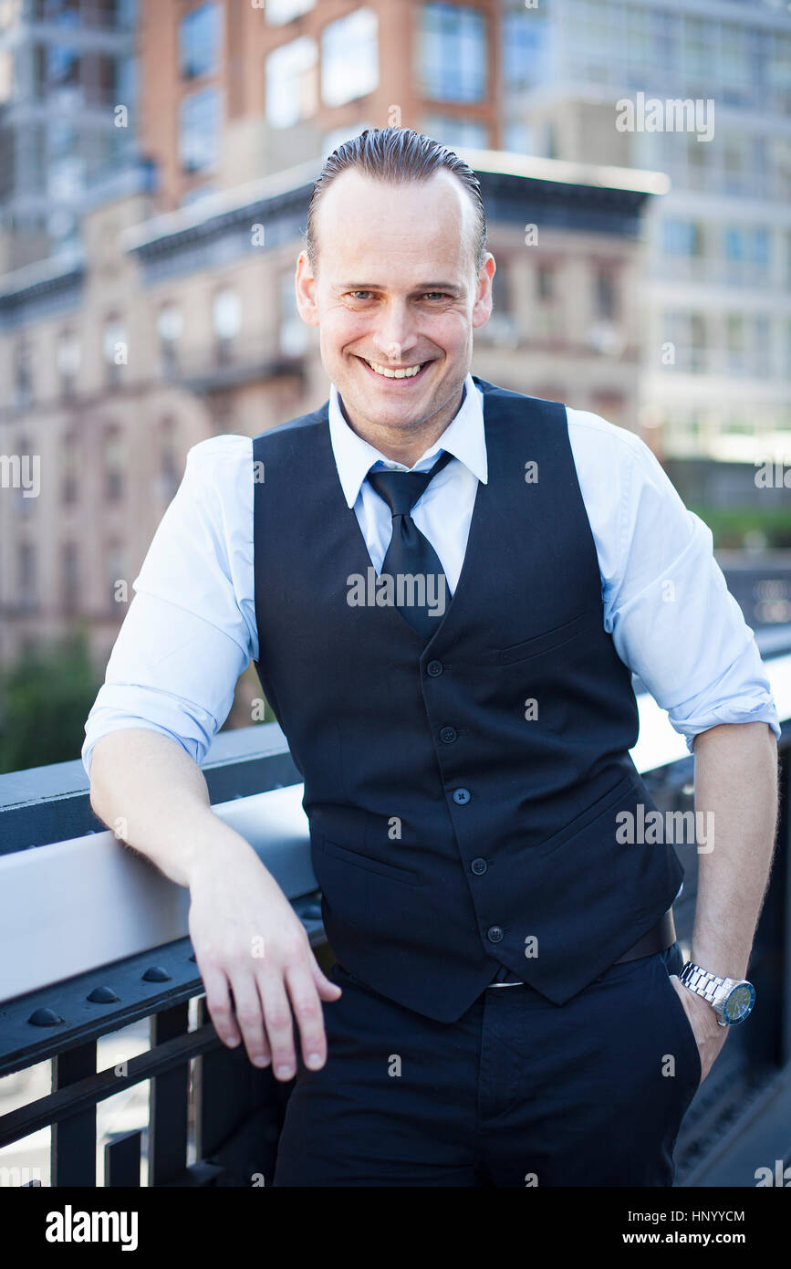 Imprenditore in piedi sul balcone, sorridente, ritratto Foto Stock