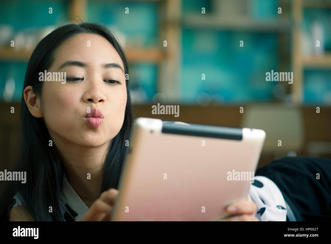 Giovane donna bacio di soffiaggio mentre in video conferenza sulla tavoletta digitale Foto Stock