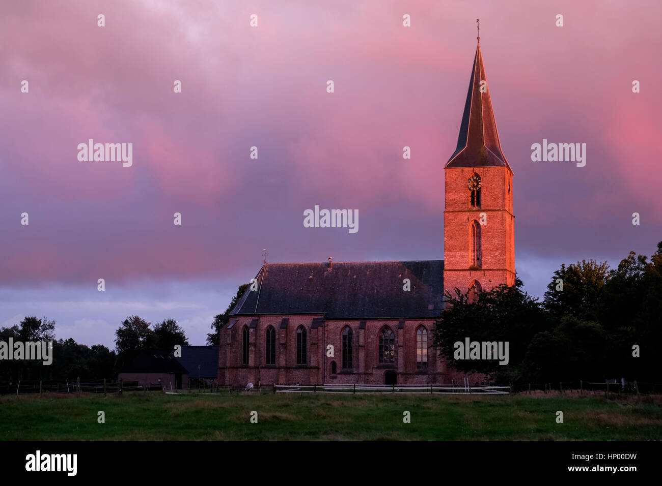 Sole di sera illuminato il campanile di una chiesa con un bagliore arancione Foto Stock