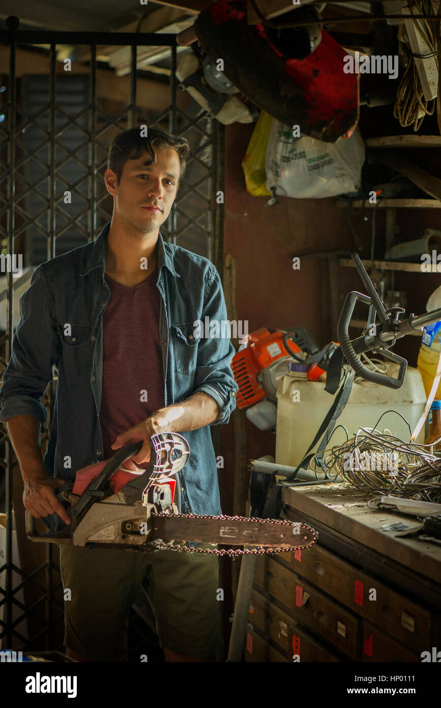 Uomo in sala archiviazione tenendo chainsaw Foto Stock