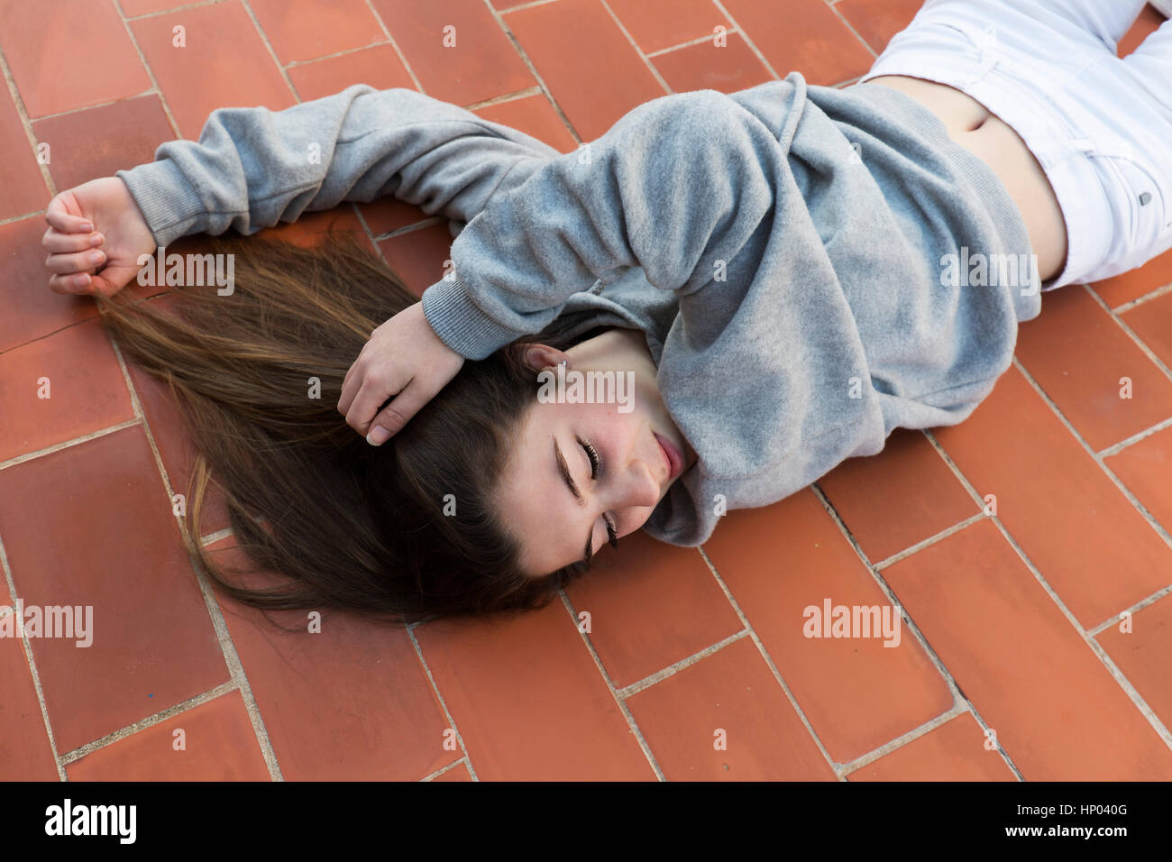 Giovane donna sdraiata sul pavimento posato. Inquadratura orizzontale con luce naturale. Foto Stock